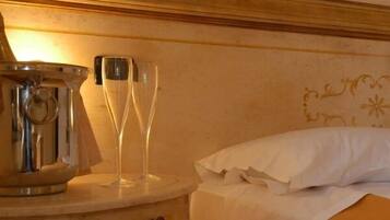 Een hotelkamer met een bed, een nachtkastje met een metalen doos en twee glaasjes.