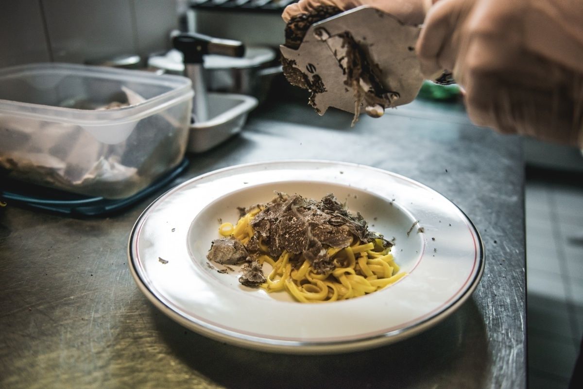 Una persona sirve un plato de espagueti con salsa oscura.