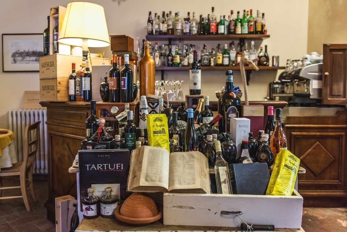 A bar area with a variety of liquor bottles, a book titled 'TARTUFI', and a lamp.