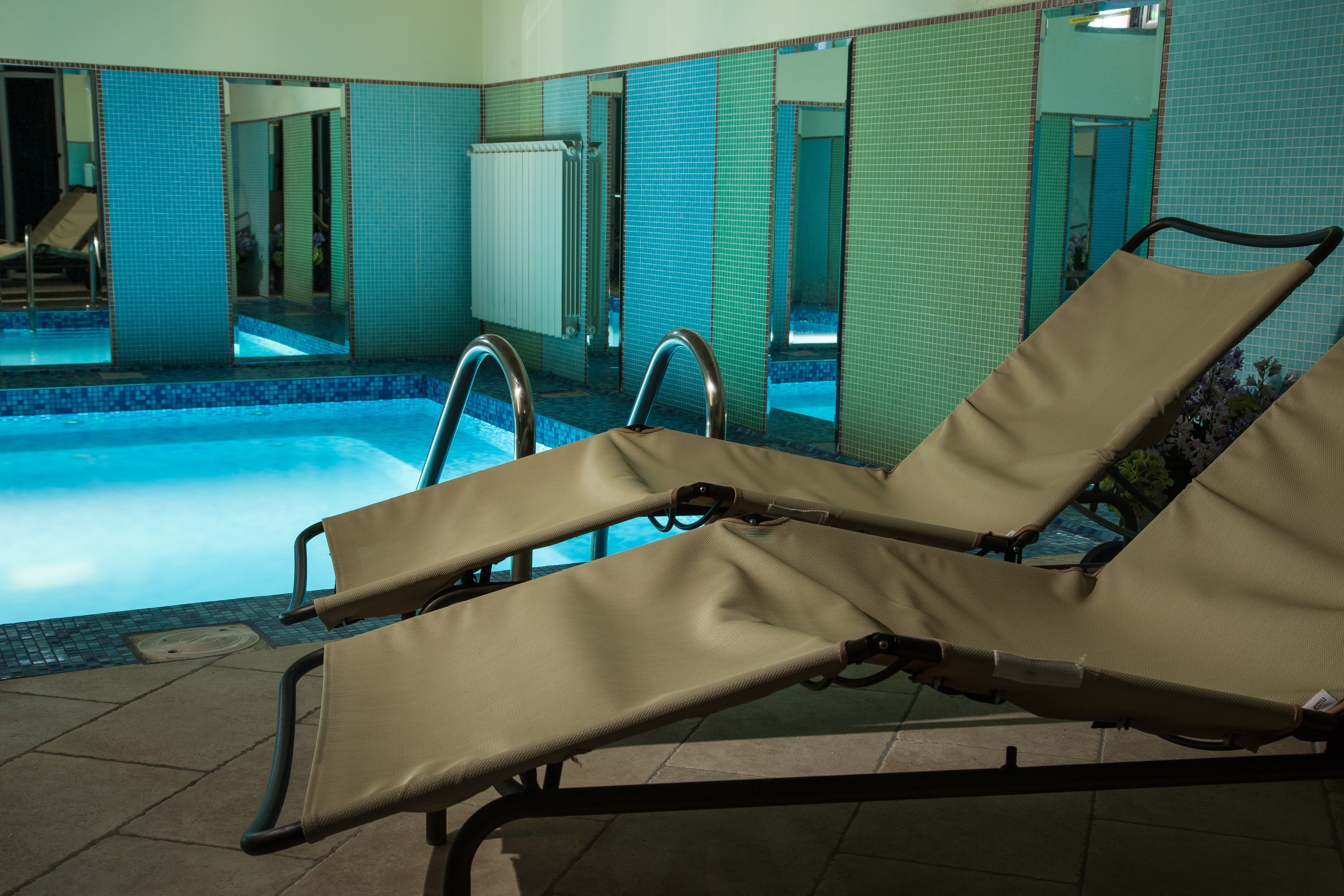 A swimming pool area with lounge chairs and a tiled wall.