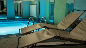 A swimming pool area with lounge chairs and a tiled wall.