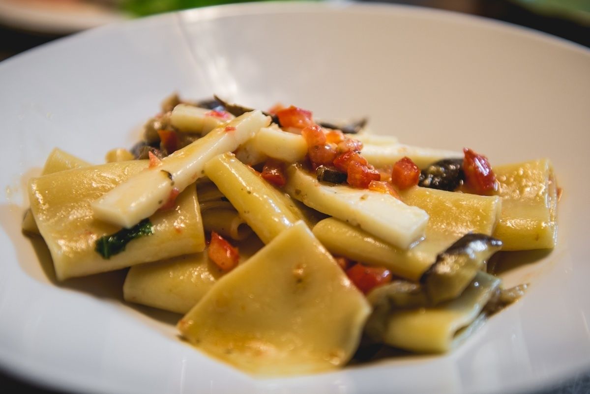 Une assiette de pâtes, de légumes et d’une sauce à base de tomates.