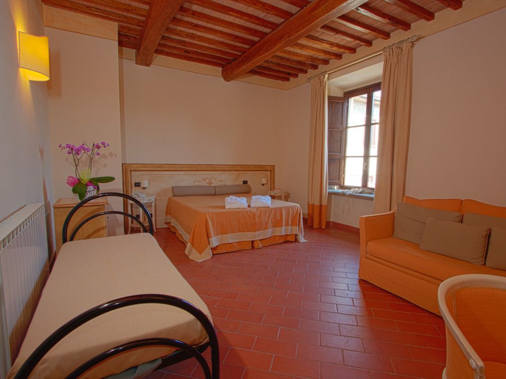 Una stanza con un letto, un divano, un tavolo e una sedia.
