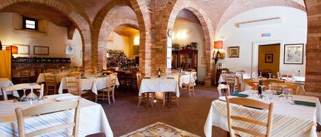 Un restaurante con arcos de ladrillo, manteles blancos y sillas de madera.