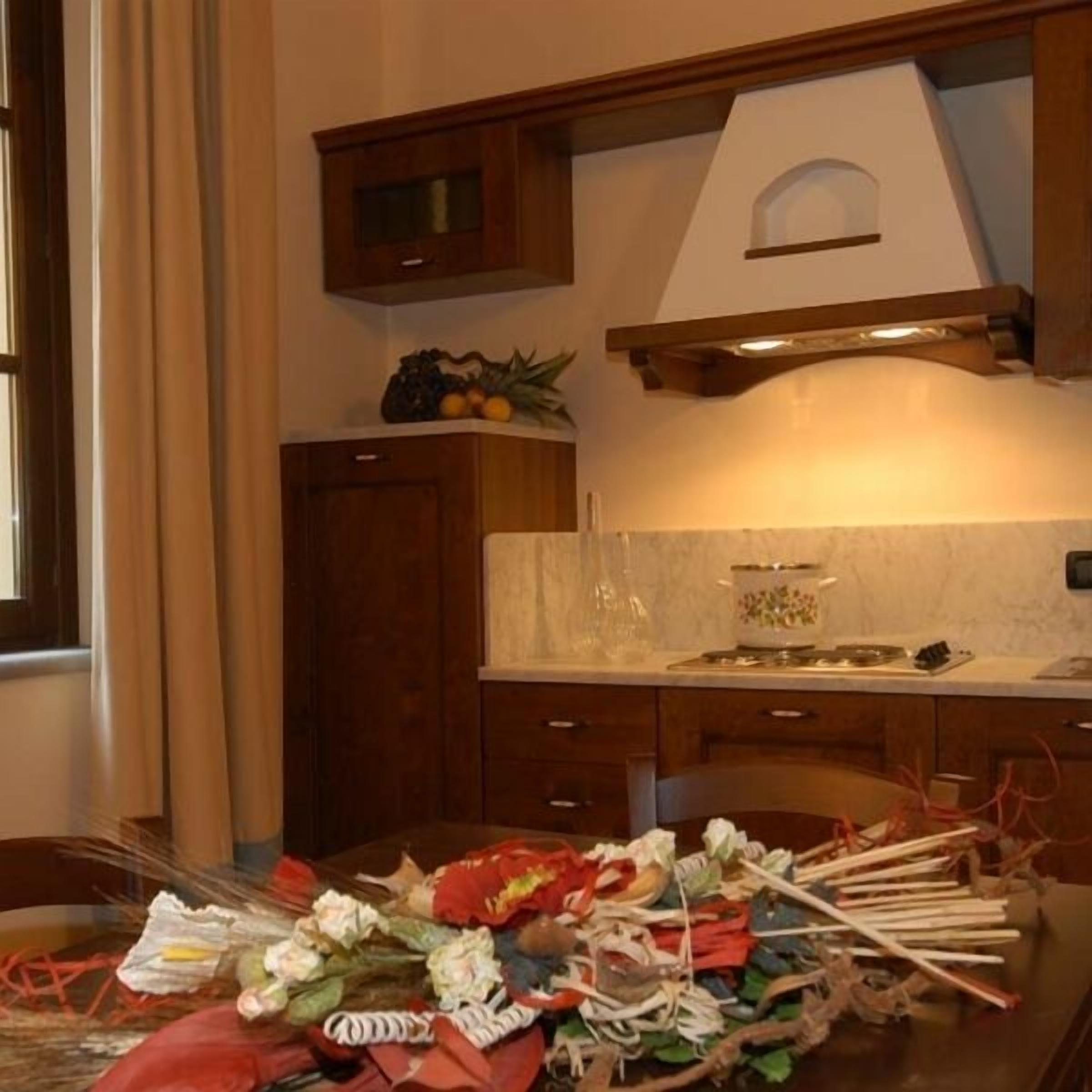 A kitchen with wooden cabinets, a marble countertop, and a variety of fruits on the shelf.