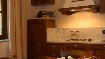 A kitchen with wooden cabinets, a marble countertop, and a variety of fruits on the shelf.