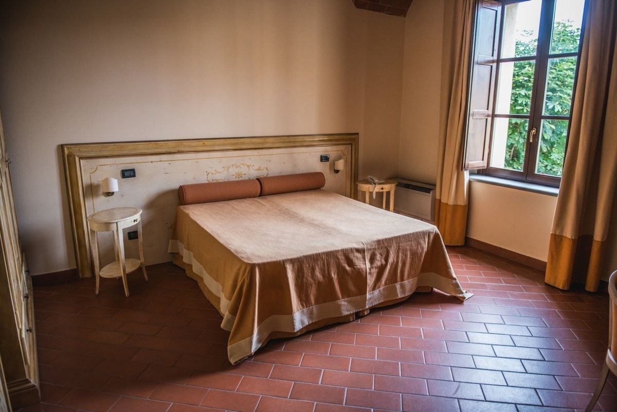 Una camera da letto con un letto grande, un tavolino e un comodino, e una finestra con tende.