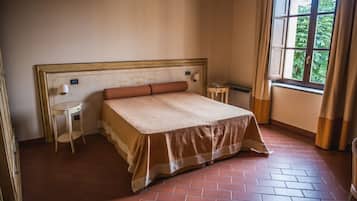 Una camera da letto con un letto grande, un tavolino e un comodino, e una finestra con tende.