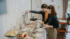 A buffet setup with various food items and a person serving food. - Mossview Resort (Khao Kho)