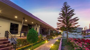 A modern building with a covered walkway, outdoor lighting, and landscaped gardens. - Mossview Resort (Khao Kho)