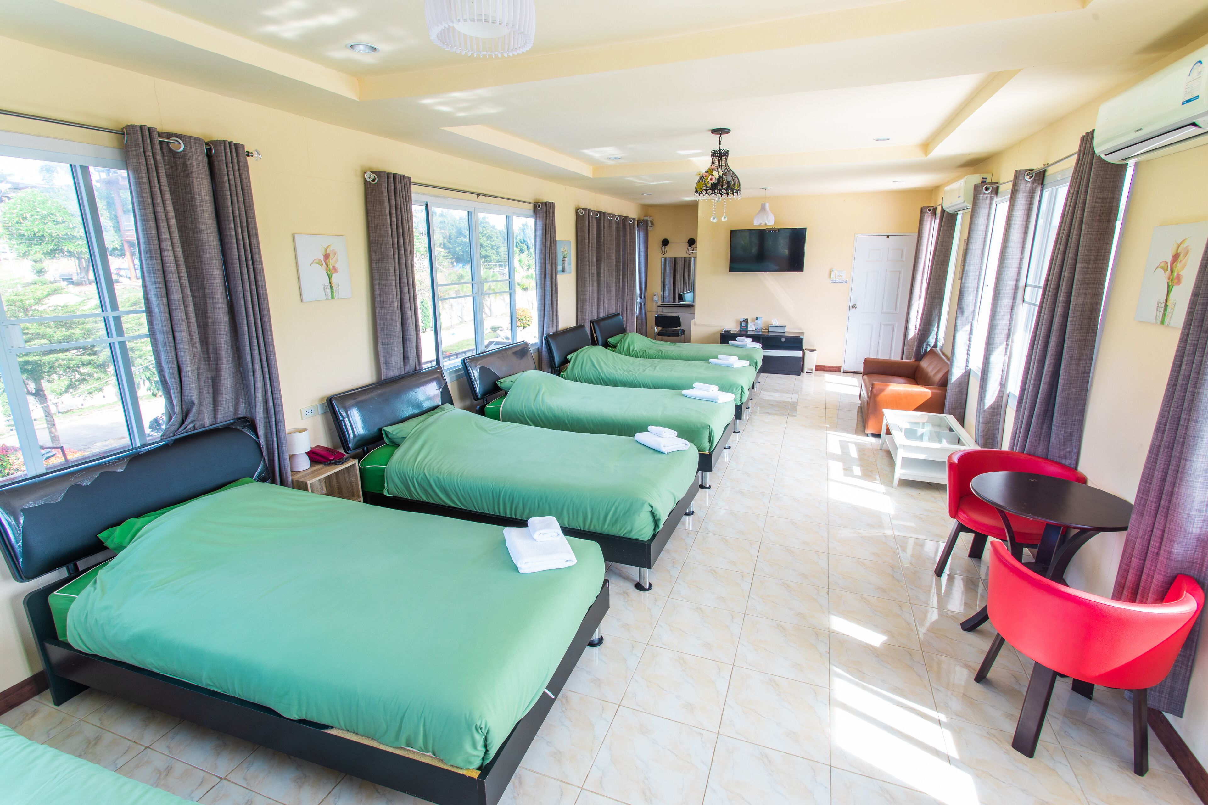 Una habitación de hotel con cuatro camas, televisión, escritorio y una silla.