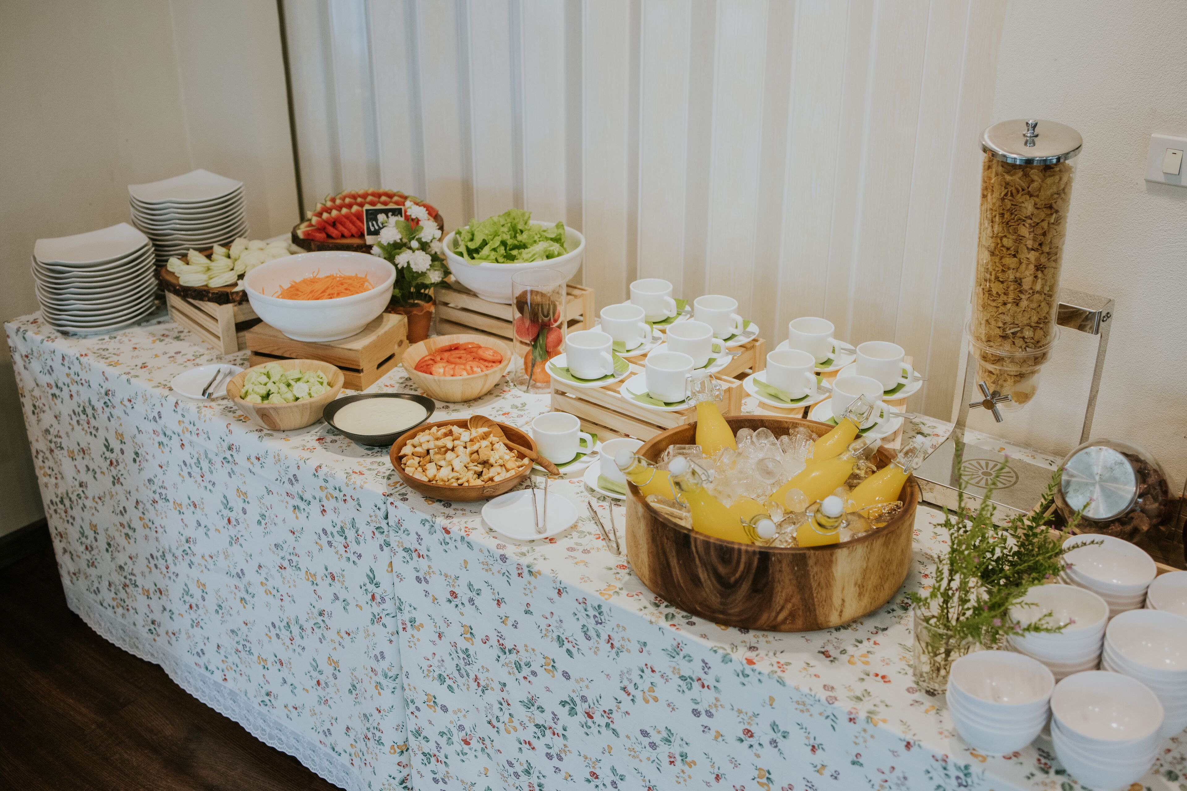 Een buffettafel met diverse gerechten en drankjes, waaronder salades, fruit en een schaal fruitsap.