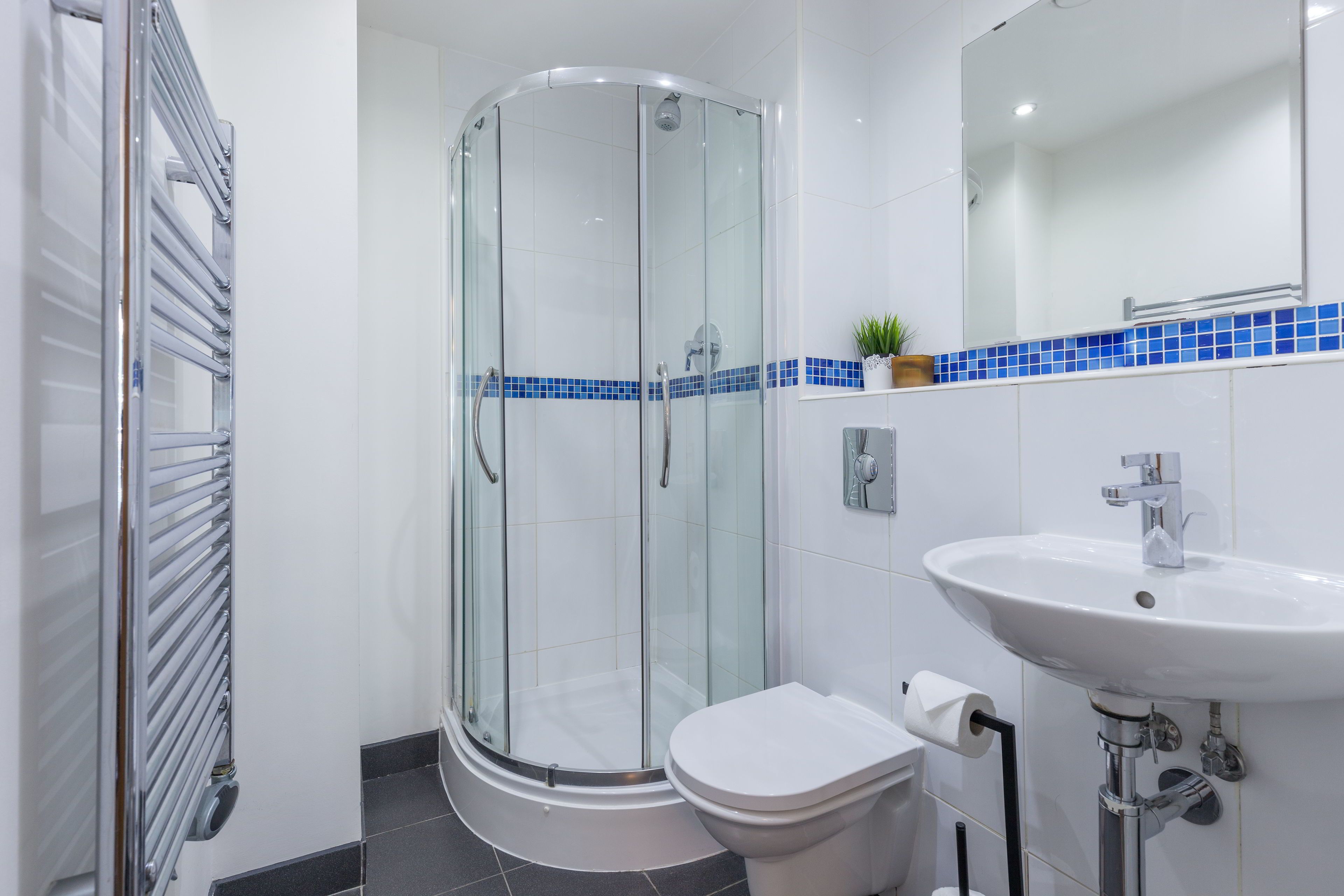 A modern bathroom with a glass-enclosed shower, a white sink, and a toilet.