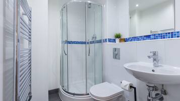 A modern bathroom with a glass-enclosed shower, a white sink, and a toilet.
