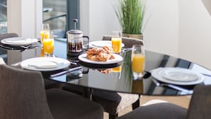 Une table de petit-déjeuner avec des assiettes, des verres et une cafetière.