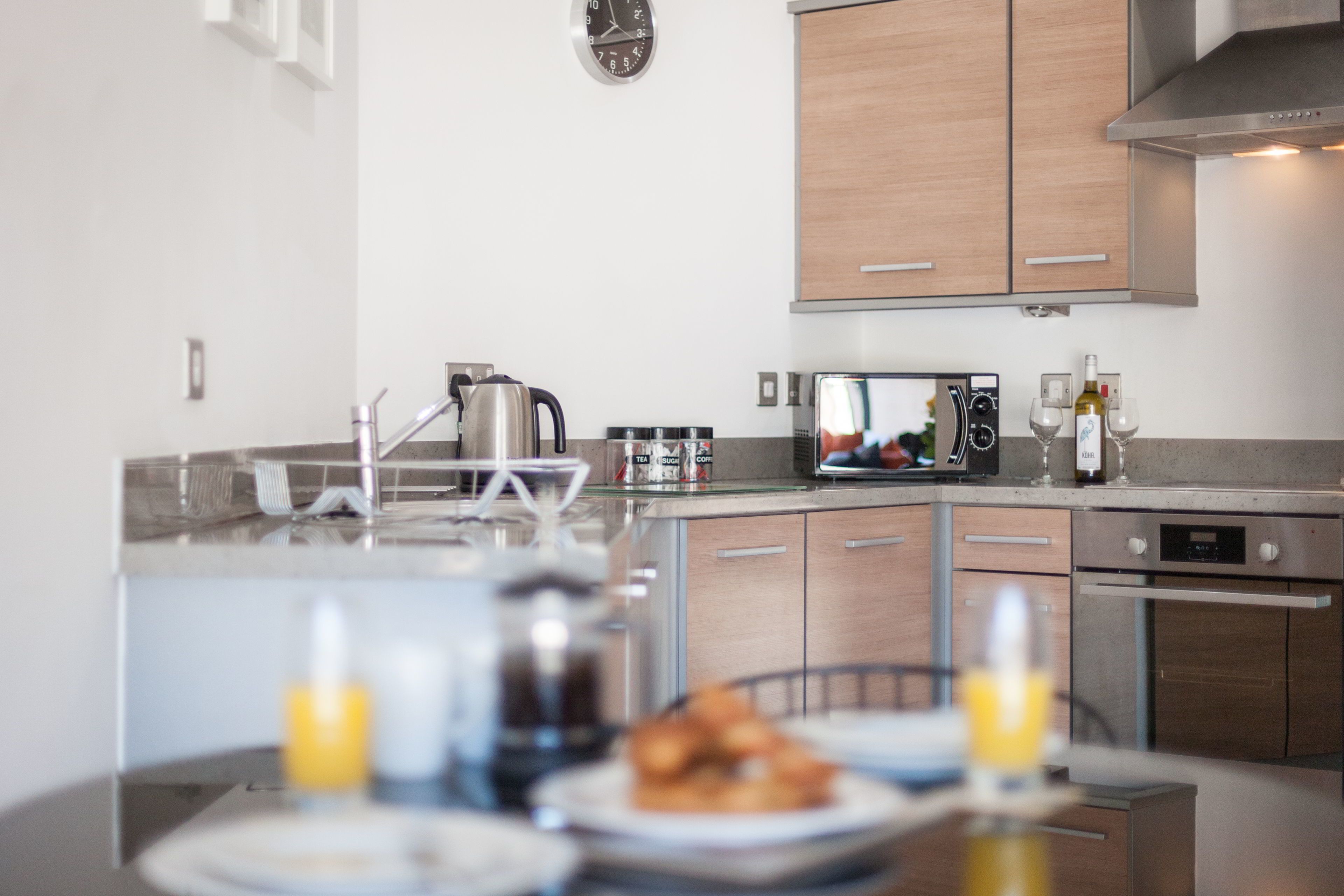 A modern kitchen with a central island, stainless steel appliances, wooden cabinets, and a microwave.