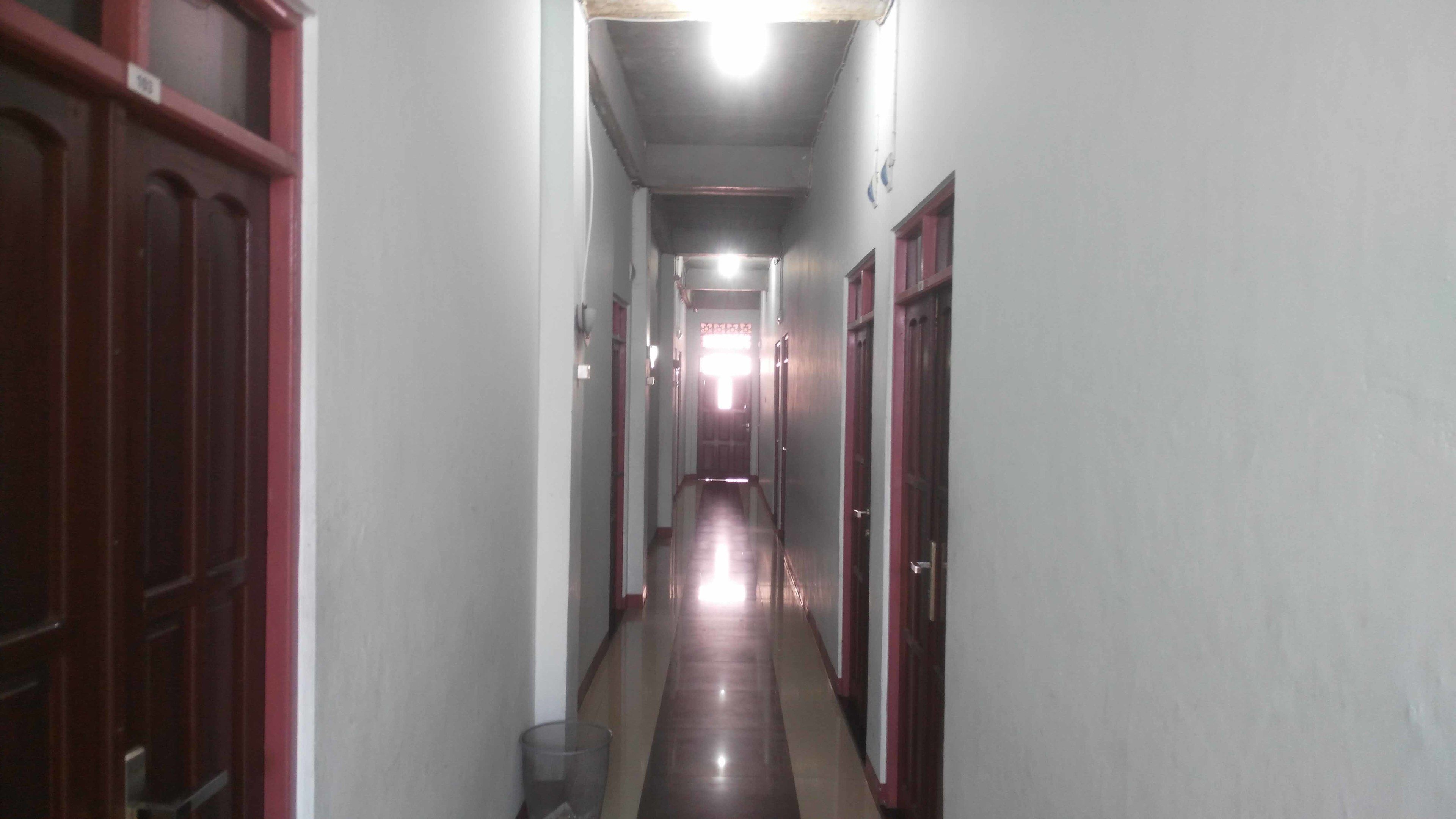 Um corredor estreito com portas em ambos os lados, dando acesso a quartos.