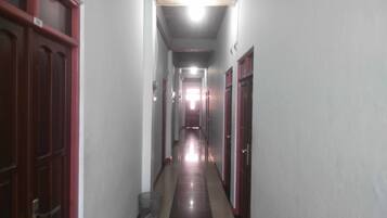 Um corredor estreito com portas em ambos os lados, dando acesso a quartos.