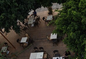 Een terras met tafels en stoelen, omgeven door bomen.
