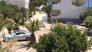 Zona residencial costera con edificios blancos, un coche aparcado y palmeras.