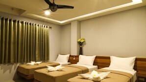 Habitación de hotel con dos camas, un ventilador de techo y un jarrón con flores.