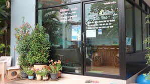 Un restaurante con puerta de vidrio y plantas en macetas afuera.