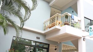 Un edificio de varios pisos con balcones, una recepción y plantas en macetas.