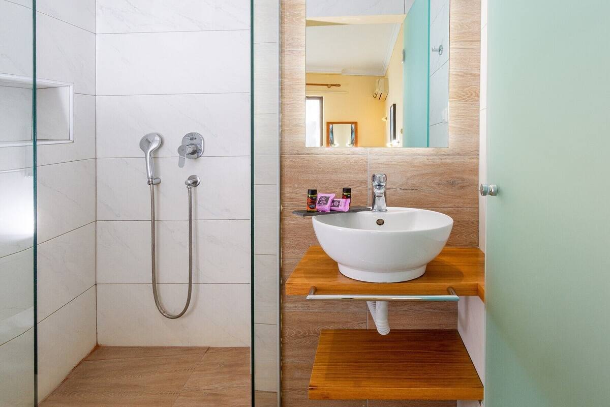 A modern bathroom with a glass-enclosed shower, a white sink, and a wooden vanity.