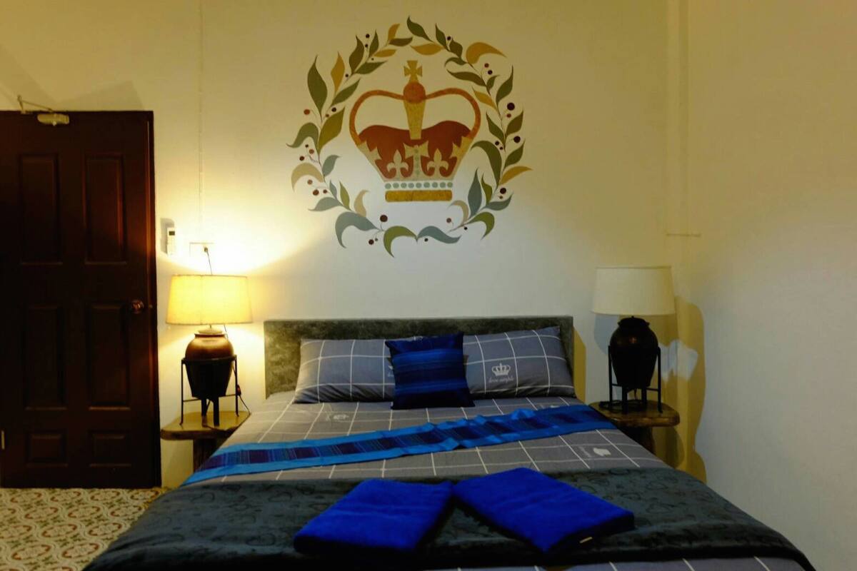 Ein Hotelzimmer mit einem Bett, einem Wandemblem und zwei Nachttischlampen.