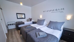 A modern hotel room with two beds, a mirror, wall-mounted lights, and a wooden floor. - Lynghagi House - Lava Water (Eyja- og Miklaholtshreppur)