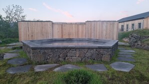 A hot tub surrounded by stone steps and a wooden fence. - Lynghagi House - Lava Water (Eyja- og Miklaholtshreppur)