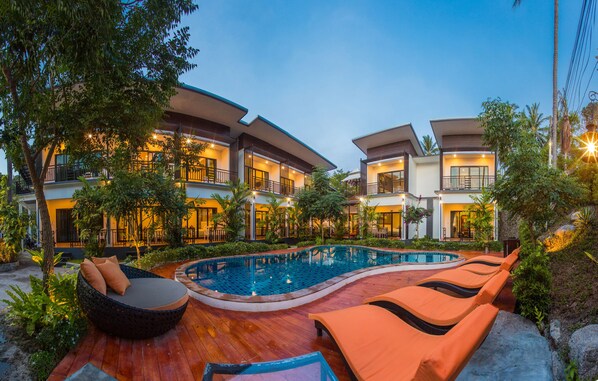 A poolside area with lounge chairs, a swimming pool, and a building with multiple balconies. - The Ozo Koh Tao (Koh Tao)