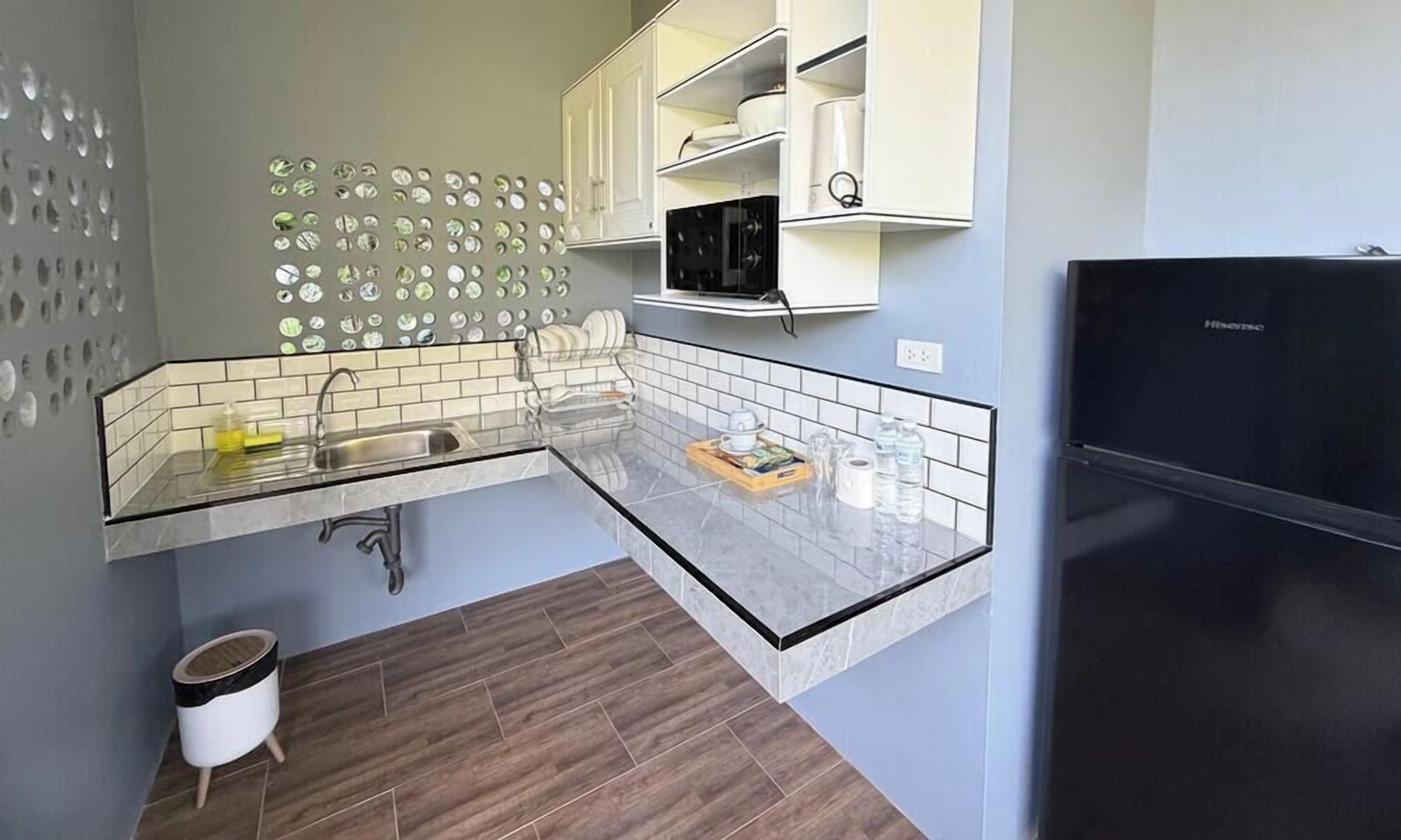 A kitchen with a built-in microwave, a black refrigerator, and a sink with a modern faucet.
