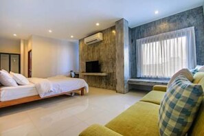 A modern bedroom with a bed, a sofa, a TV, and a window with curtains. - Sai Hometel (Koh Tao)