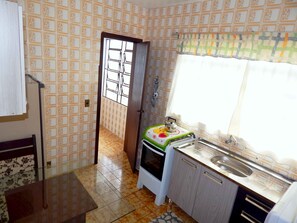 A compact kitchen with a window, a sink, and a stove. - Apartamento do Centro (Canela)