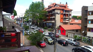 Une rue animée en milieu urbain, avec de nombreuses voitures, des immeubles et une maison rouge.