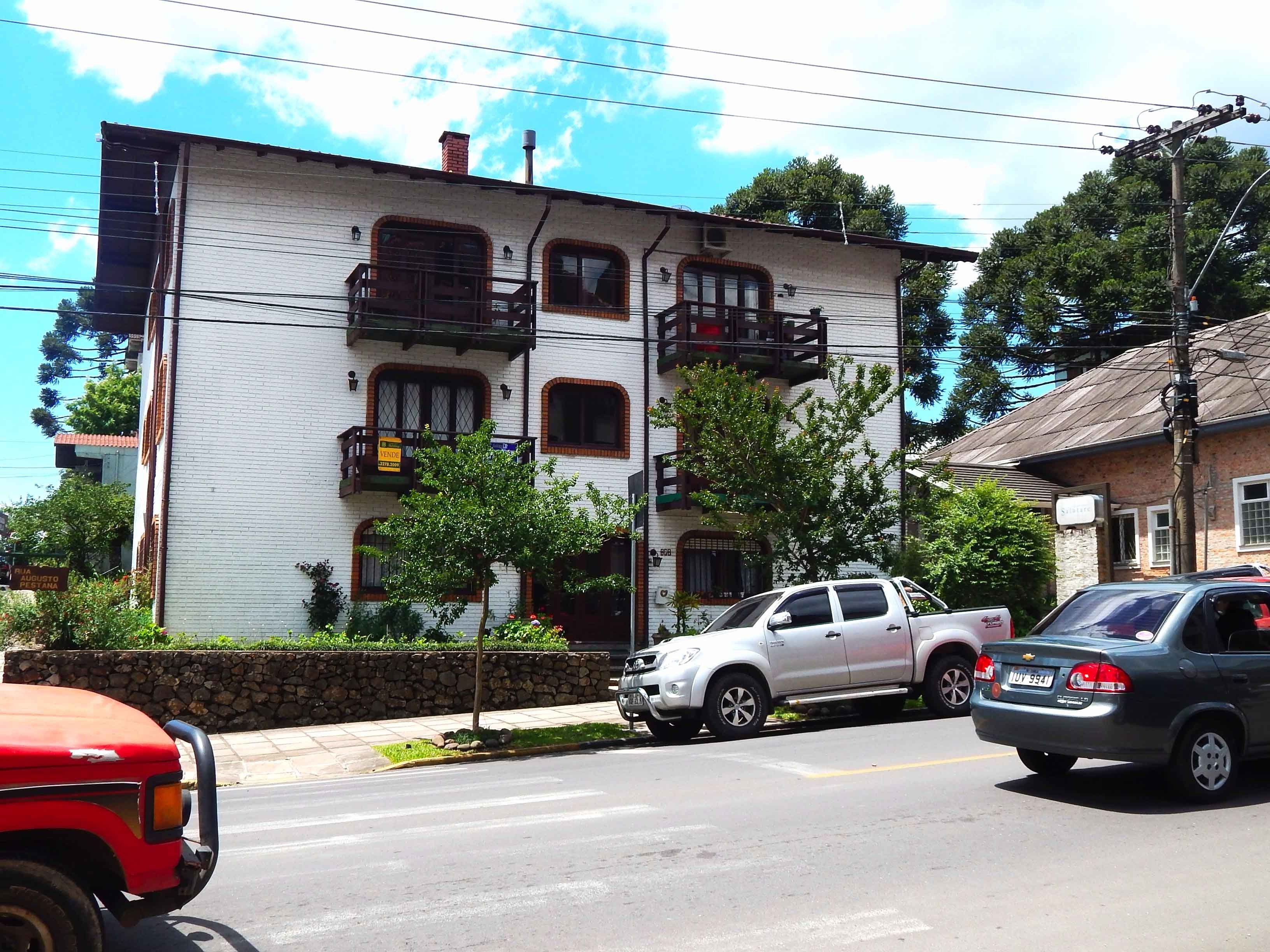 A two-story building with a white facade and multiple windows, some with shutters.