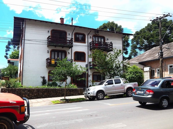 A two-story building with a white facade and multiple windows, some with shutters.