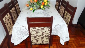 Une table à manger agrémentée d’un centre de table floral, entourée de six chaises dont les sièges sont recouverts d’un tissu à motifs.