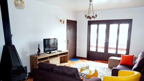 Un salon avec un téléviseur, un canapé et un fauteuil jaune.