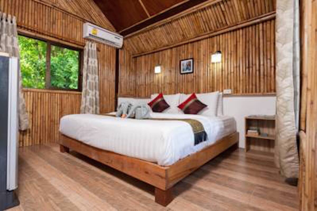 A wooden-paneled bedroom with a bed, a bedside table, and a window with curtains.