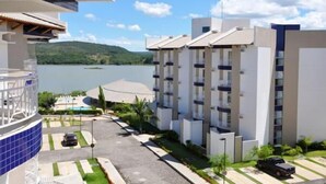 A modern hotel with a pool, a view of the lake, and a parking area. - Enseada Residence (Caldas Novas)