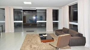 A modern living room with a sofa, a coffee table, and a rug. - Enseada Residence (Caldas Novas)