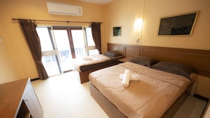 A hotel room with two beds, a desk, and a window with curtains.