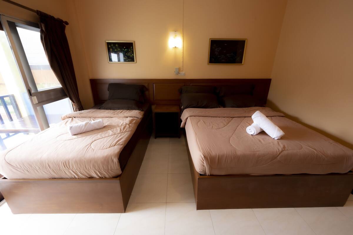 A hotel room with two beds, a nightstand, and a window with curtains.