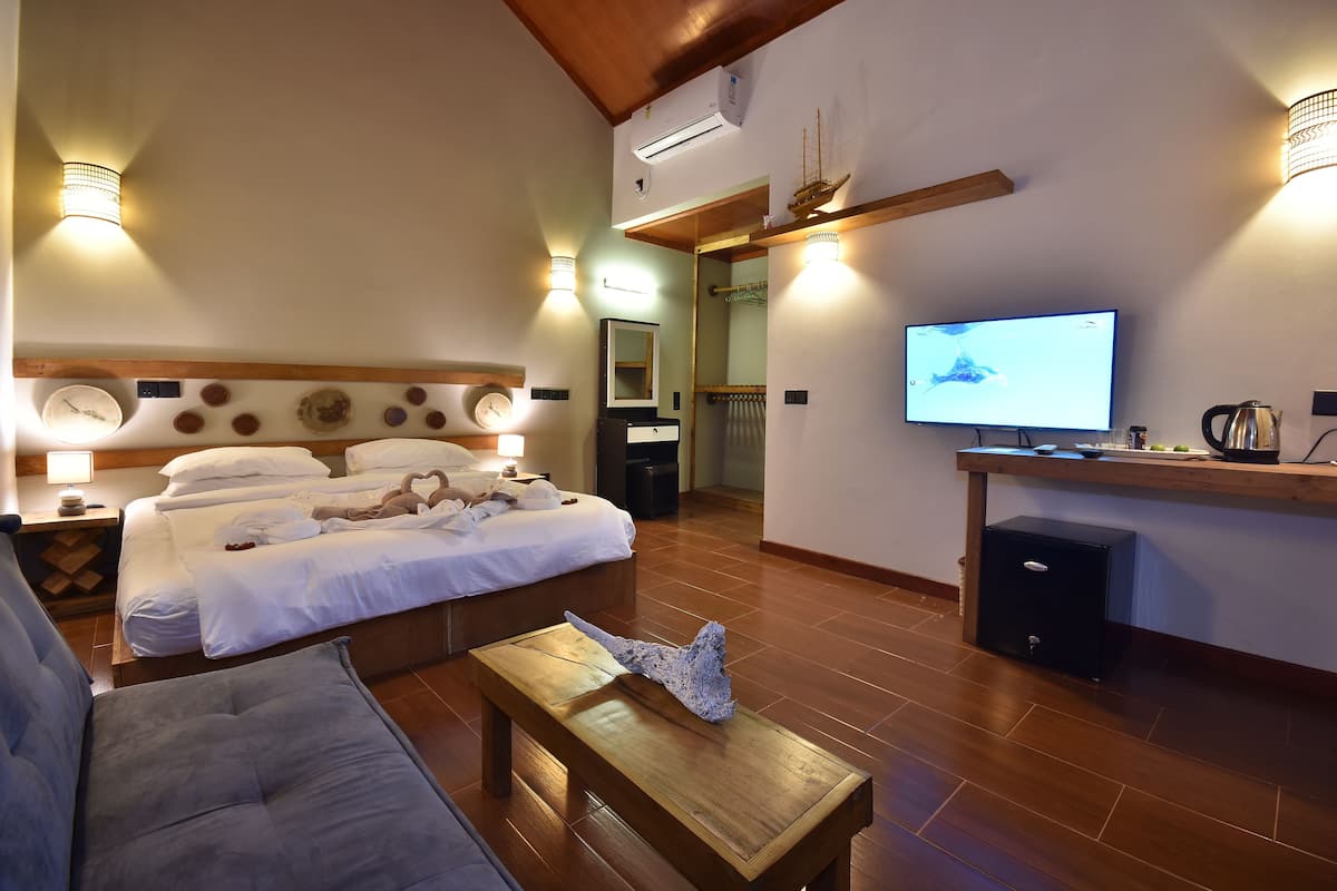 A hotel room with a bed, a TV, a wooden coffee table, and a sofa.