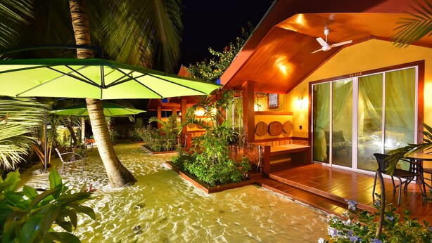 Um resort tropical com área de piscina, mobiliário de exterior e um alpendre coberto.