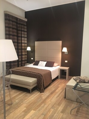 A modern bedroom with a large bed, bedside tables, a bench, and a floor lamp.