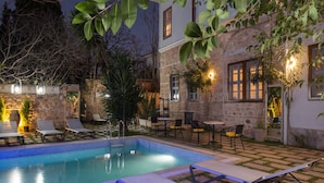 A pool area with lounge chairs and a stone building with windows. - Delight Deluxe Hotel (Antalya)