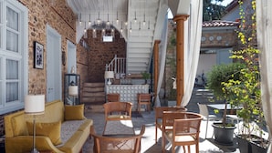 A cozy outdoor seating area with a sofa and chairs, a stone wall, and a staircase leading to an upper level. - Delight Deluxe Hotel (Antalya)